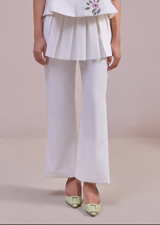 Person wearing a white outfit with floral embroidery on a plain background