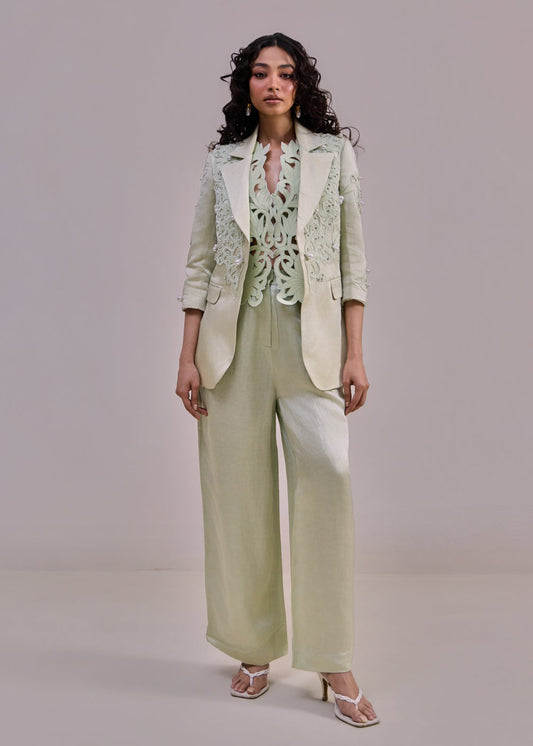 Woman wearing a light green suit with a matching blouse against a plain background