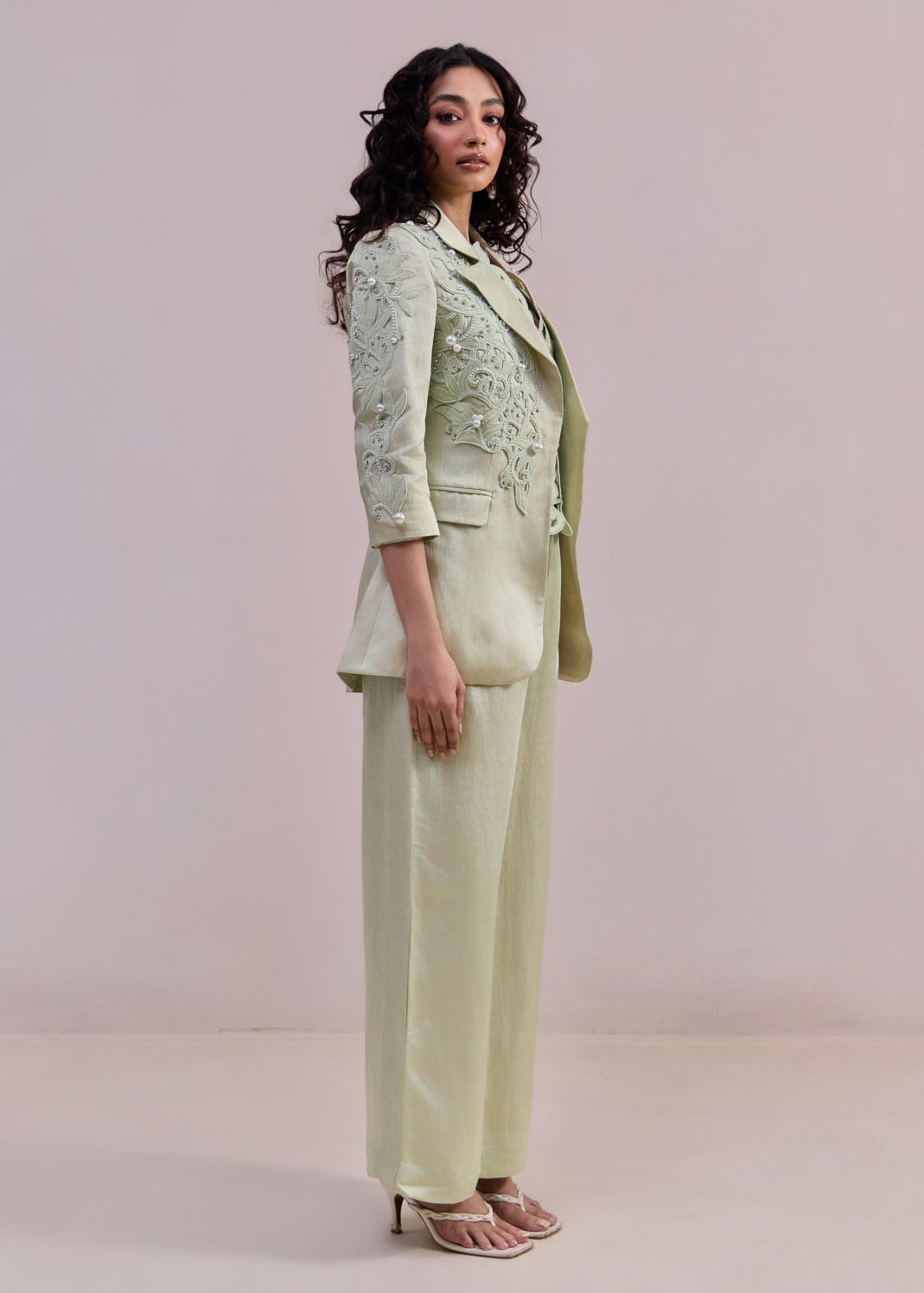 Woman wearing a light green suit against a plain background