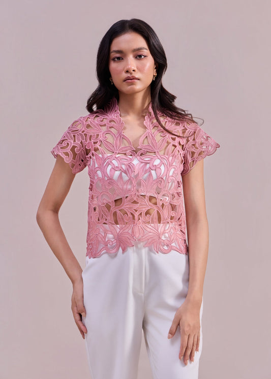 Woman wearing a pink lace top against a light pink background