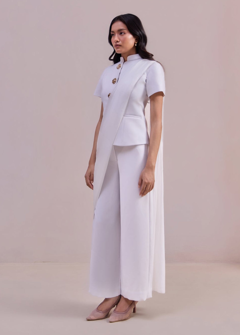 Woman wearing a white outfit against a plain background