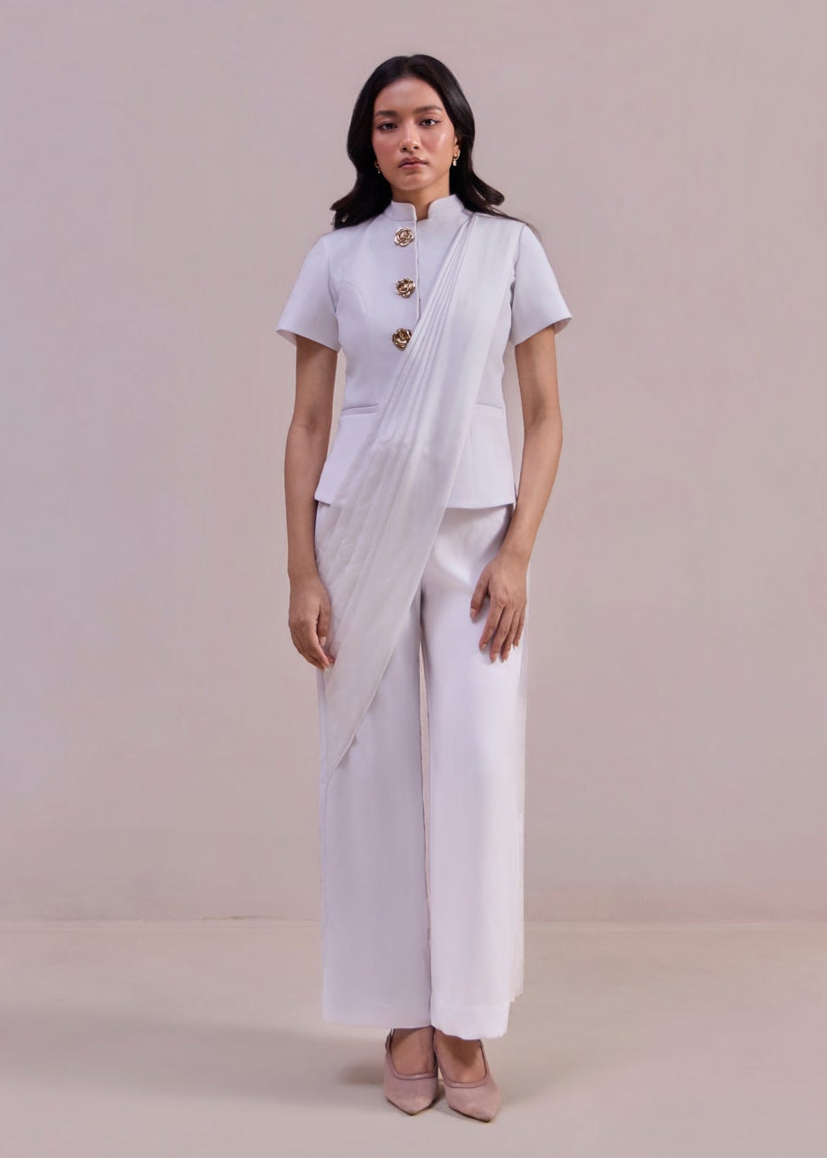 Woman wearing a white outfit with a sari on a plain background