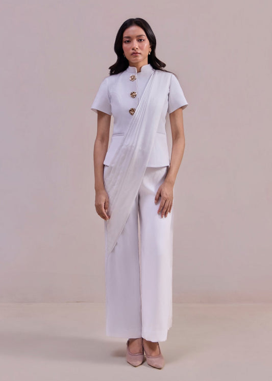 Woman wearing a white outfit with a sari on a plain background