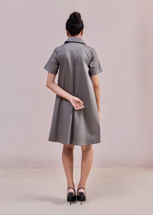 Woman wearing a gray dress against a plain background