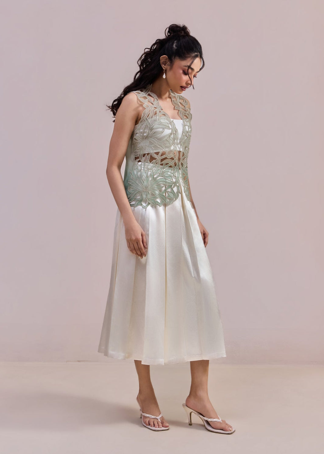 Woman wearing a light green sequined top and white skirt against a plain background