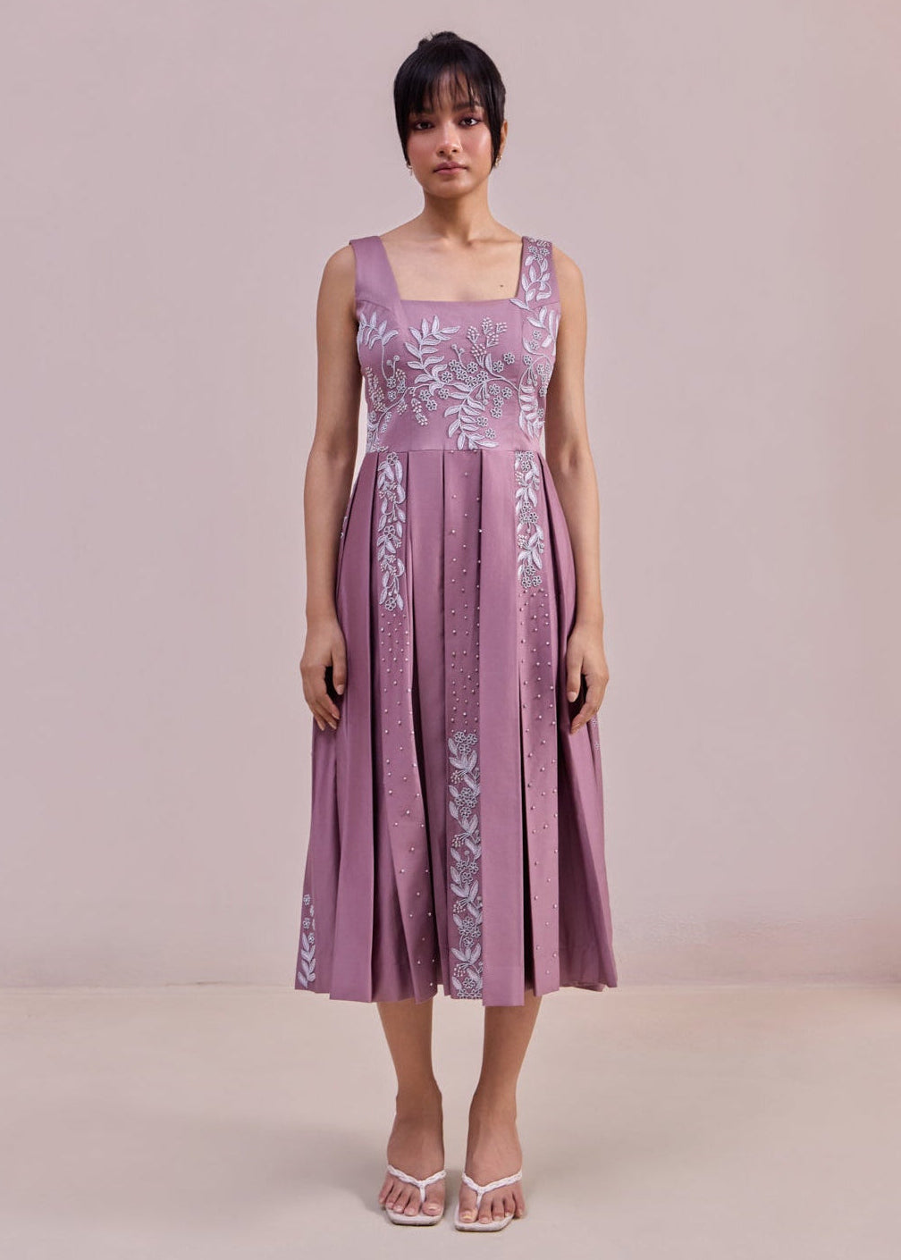 Woman wearing a purple dress with floral patterns against a plain background