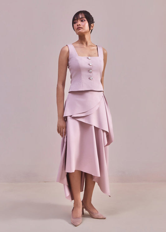 Woman wearing a light pink sleeveless top and skirt set against a plain background