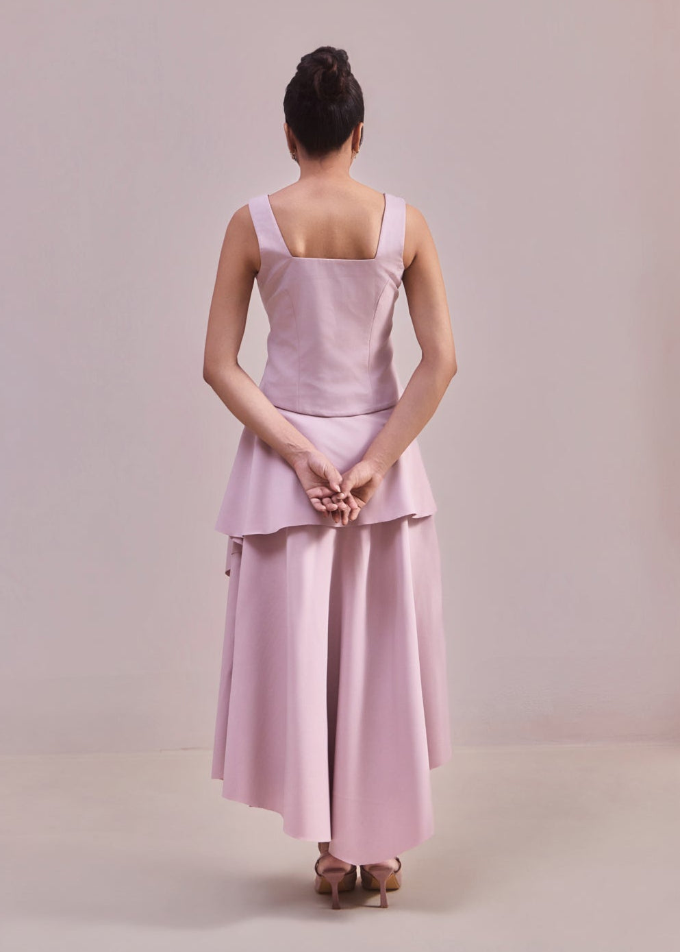 Person wearing a light pink dress with a plain background