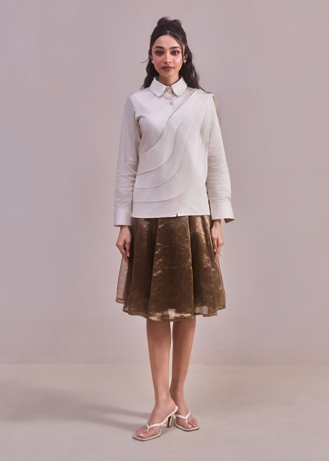 Woman wearing a light gray blazer and brown skirt against a plain background