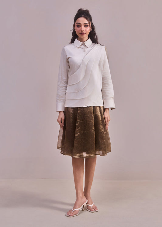 Woman wearing a light gray blazer and brown skirt against a plain background