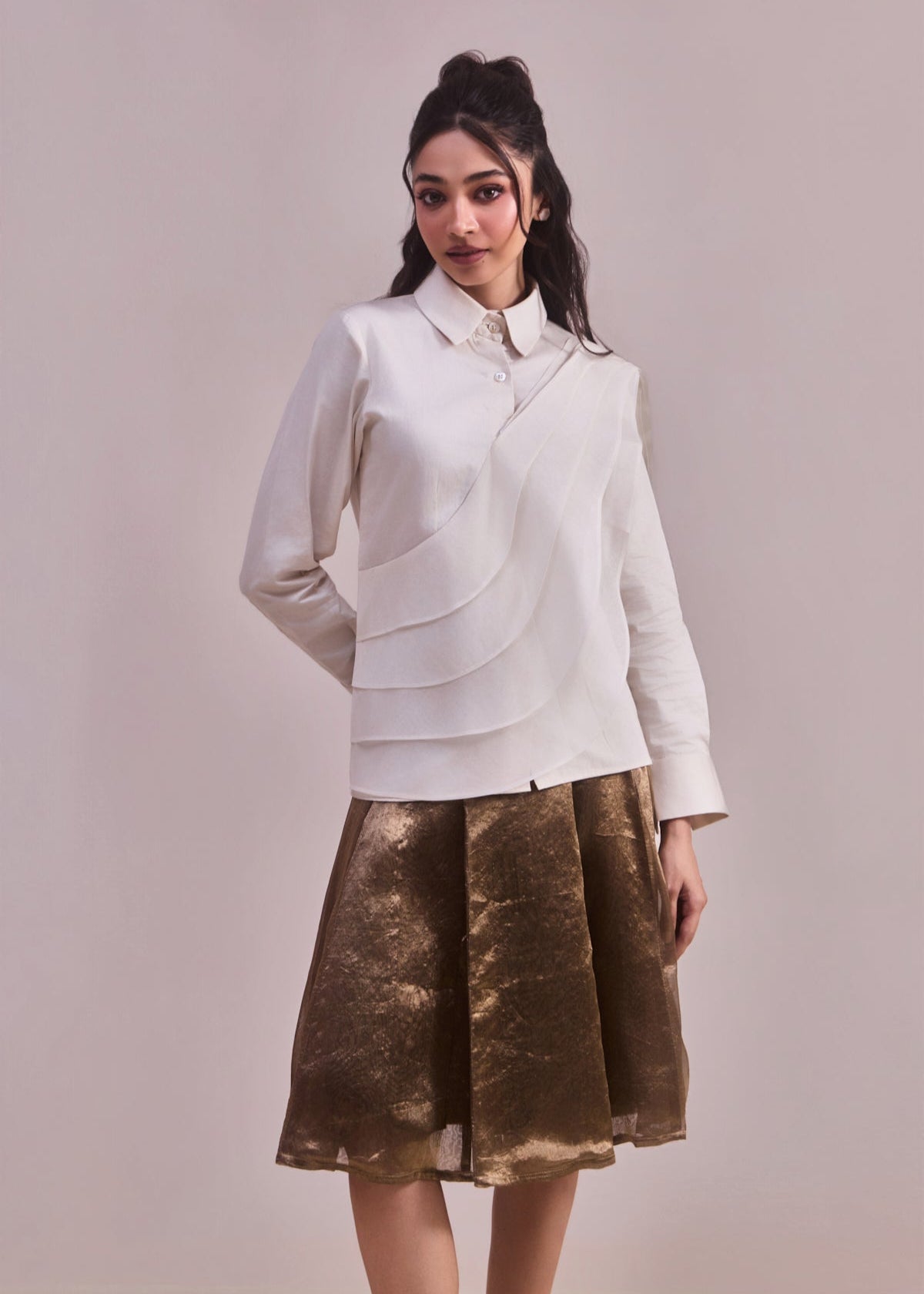 Woman wearing a white blouse and brown skirt against a plain background
