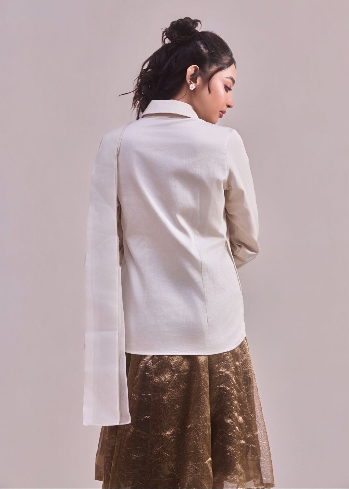 Woman wearing a white blouse and brown skirt against a plain background
