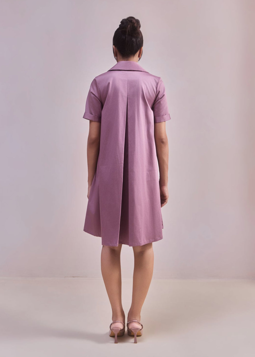 Woman wearing a pink dress against a plain background
